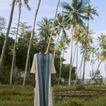 Man standing in a grassy area with palm trees in the background