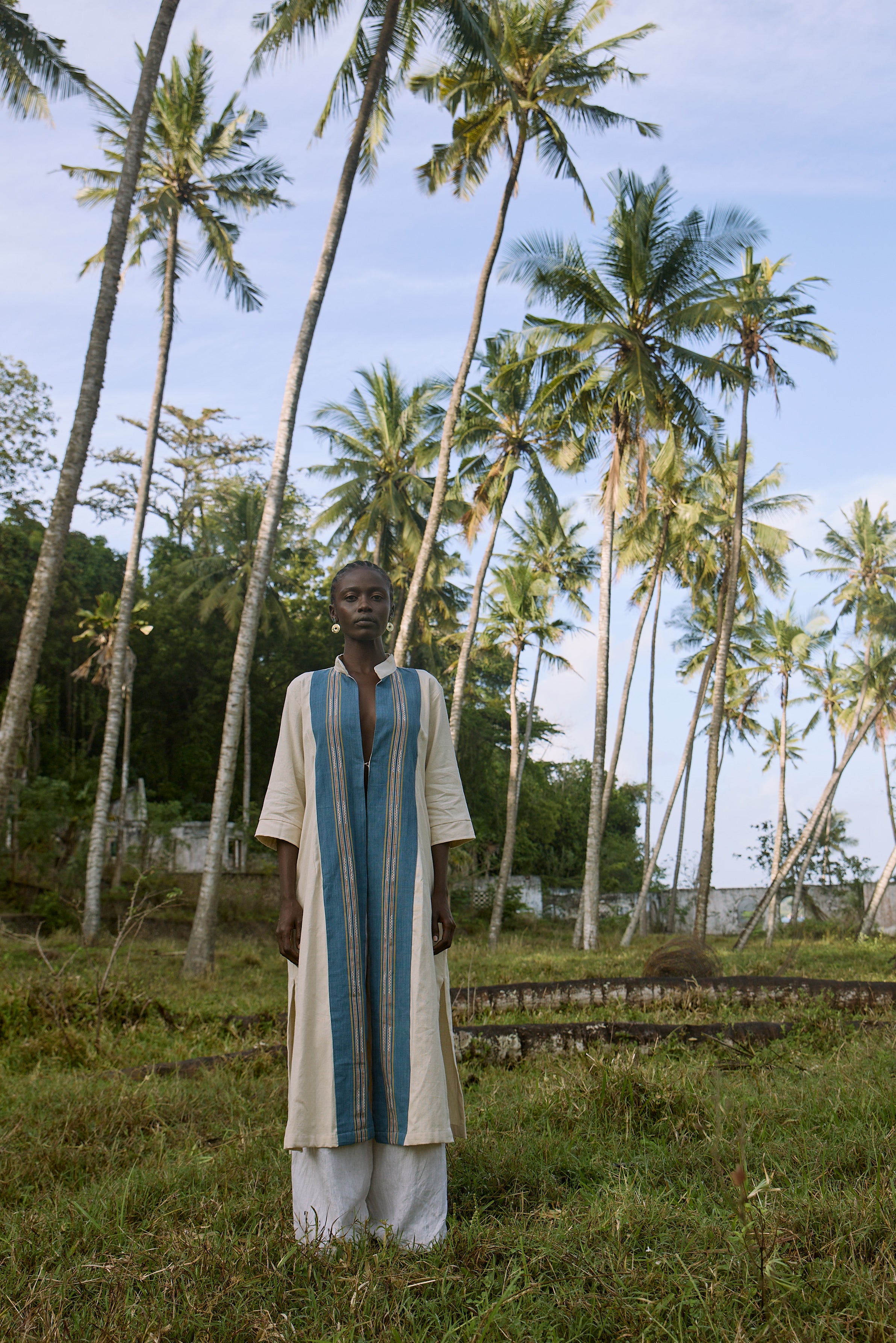 Man standing in a grassy area with palm trees in the background