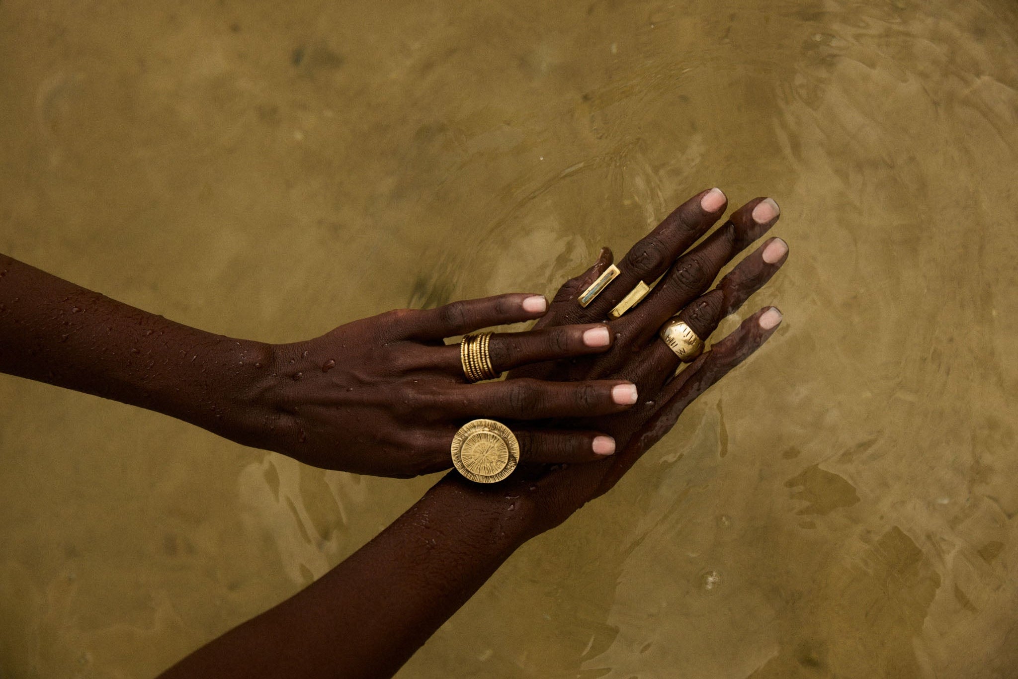 Hands with gold jewelry on a textured brown background