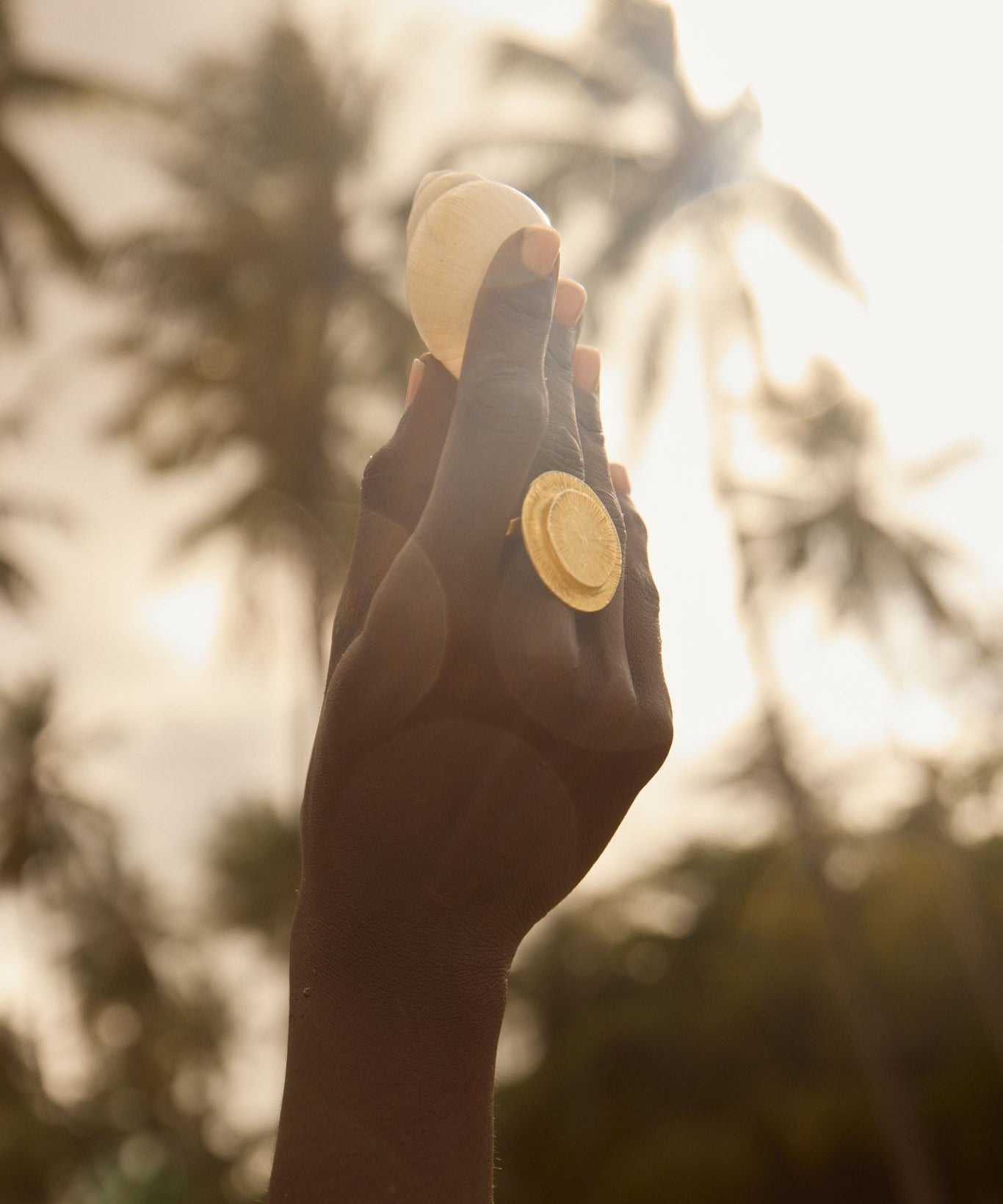 Hand holding a small object with a blurred natural background