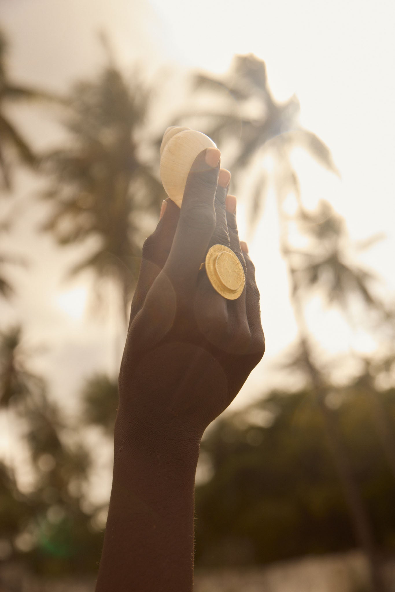 Hand holding a small object with a blurred natural background